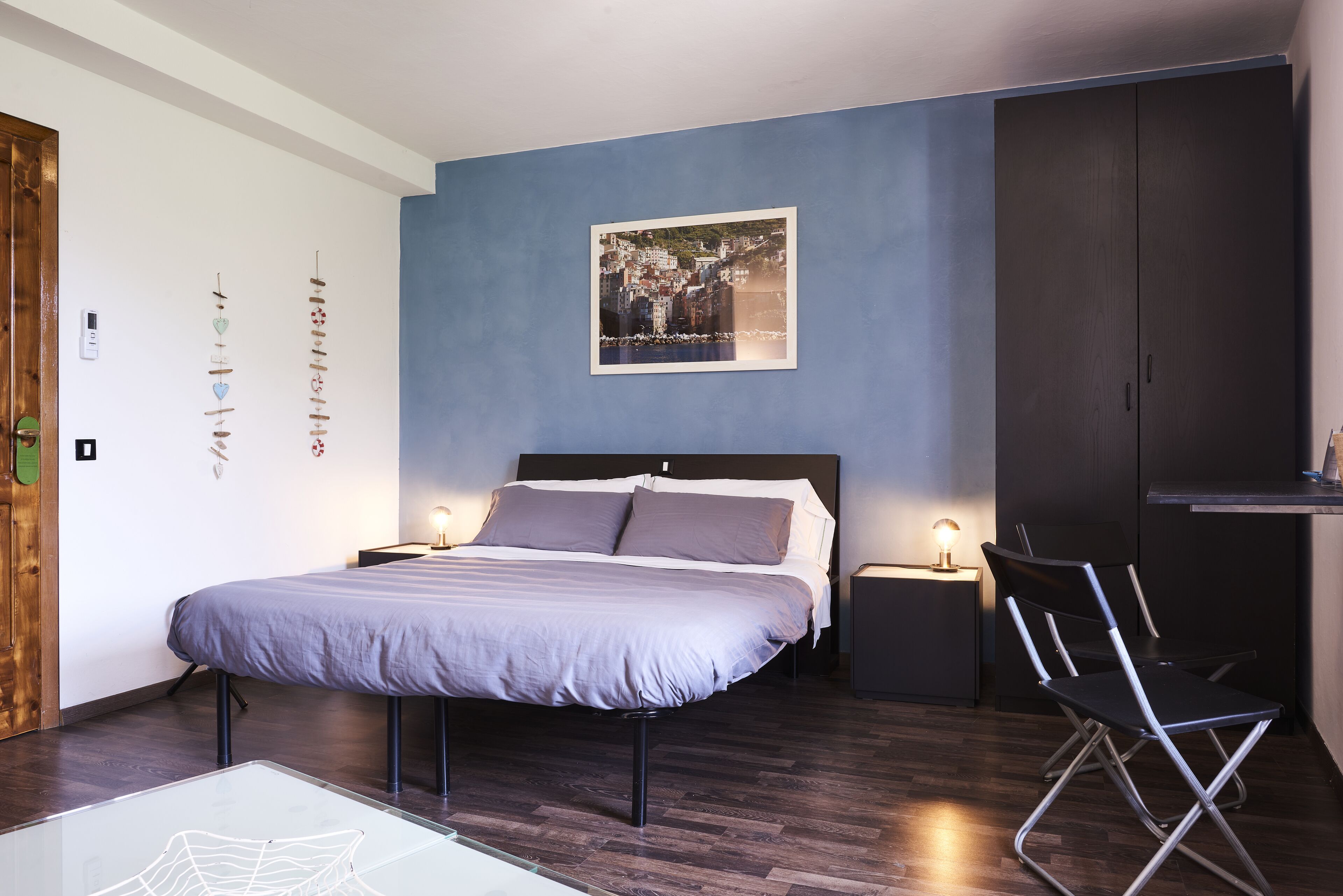 A modern bedroom with a large bed, bedside tables, a desk, and a chair.