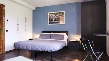 Un dormitorio moderno con una cama grande, mesitas de noche, un escritorio y una silla.