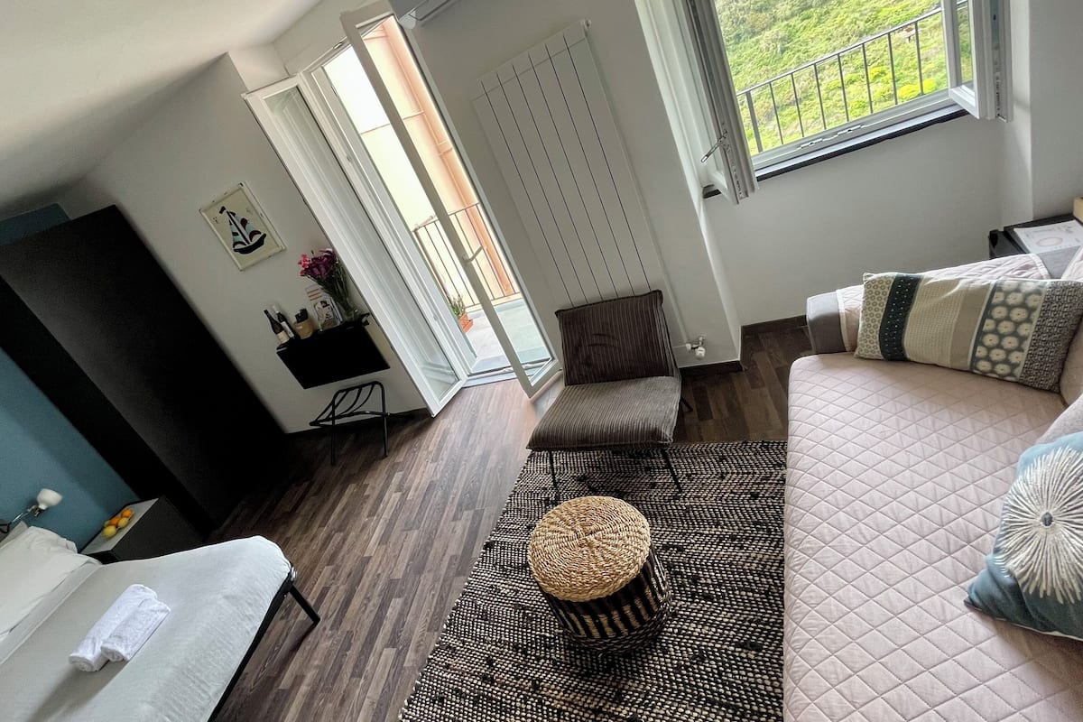 A modern living room with a sofa, a coffee table, a TV, and a balcony with a view.
