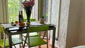 Una habitación con una cama, una mesa con sillas, un televisor montado en la pared y vistas al verde a través de la ventana.