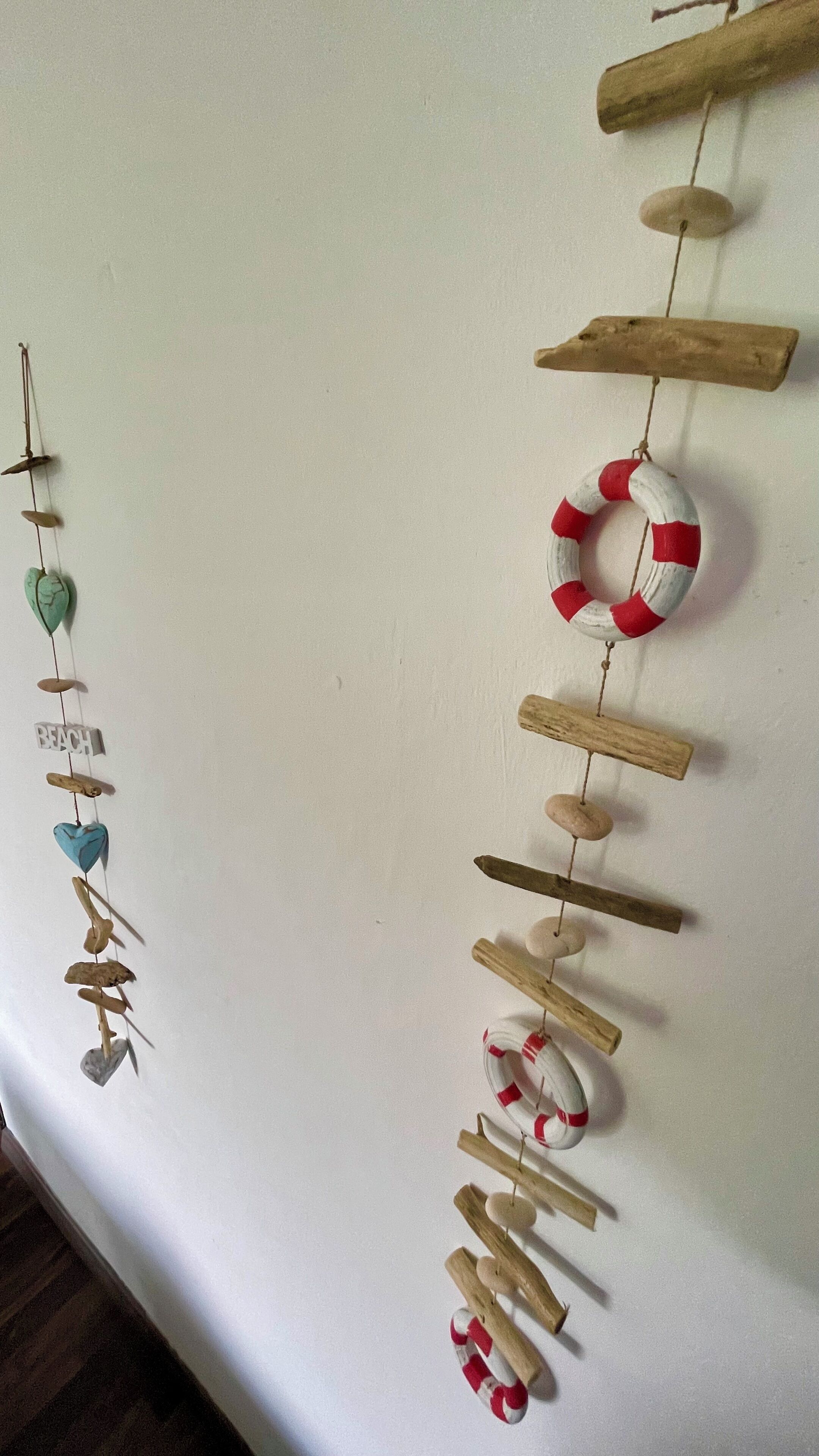 A wall with a decorative arrangement of wooden sticks and various objects, including a lifebuoy and a sign that says "BEACH".