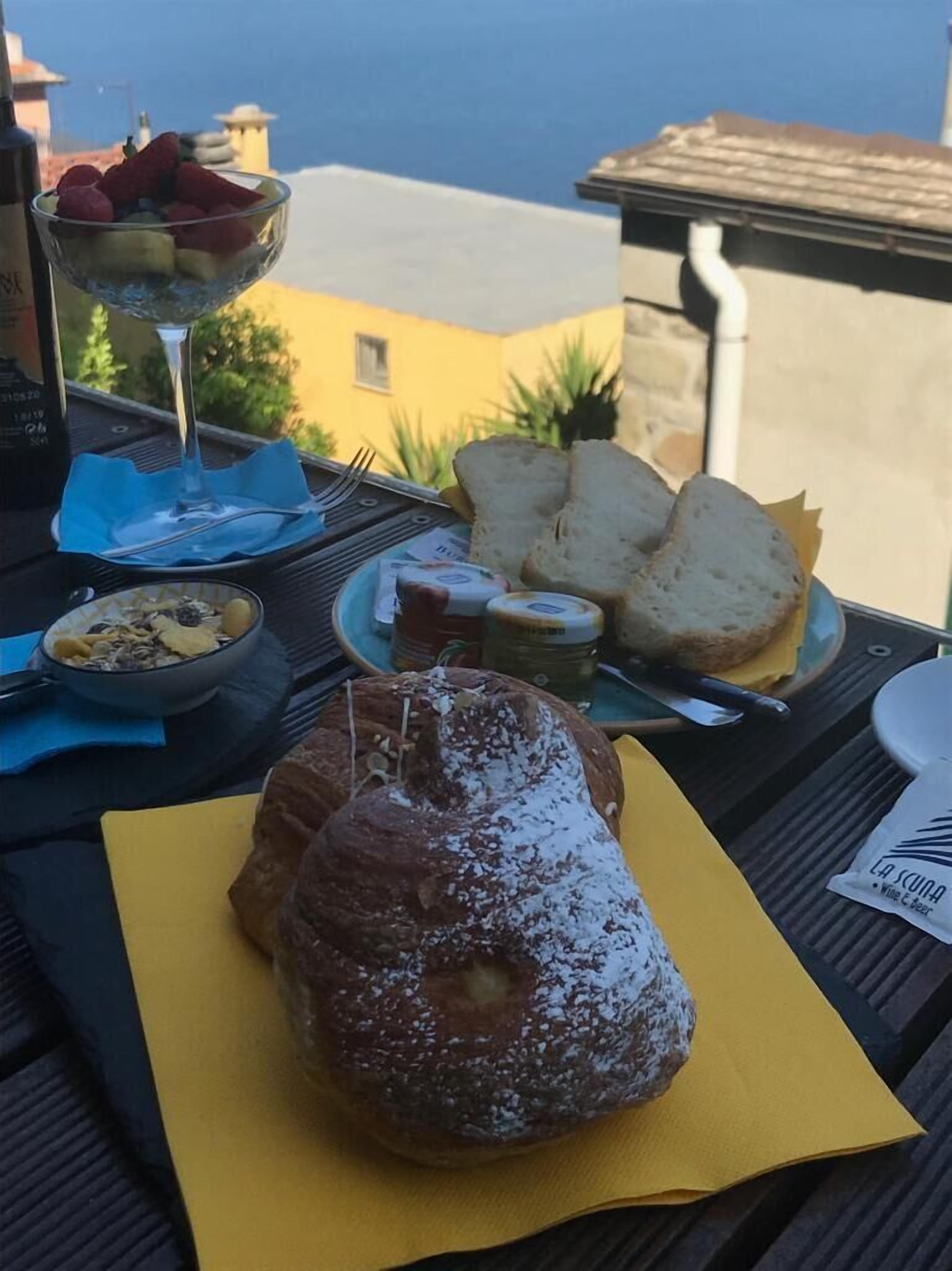 A table with food and drinks, a view of buildings, and a bottle of wine.