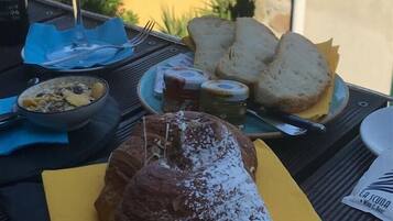 A table with food and drinks, a view of buildings, and a bottle of wine.