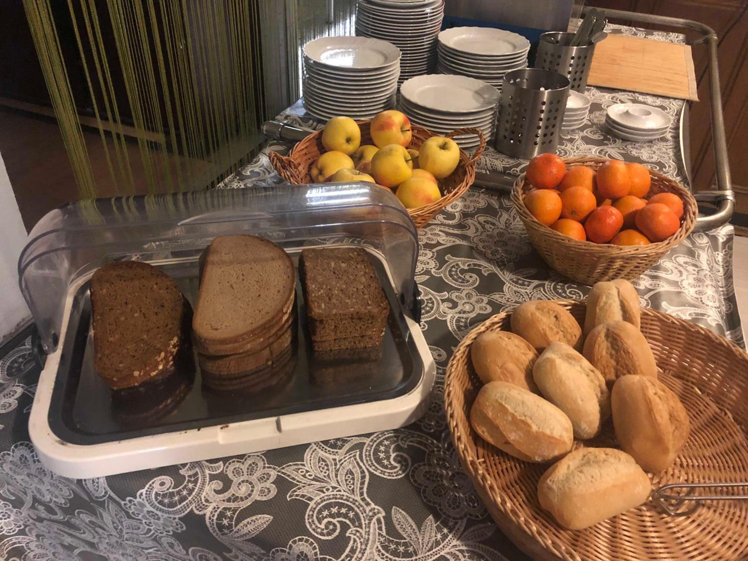 Una mesa de buffet con pan, frutas y platos.