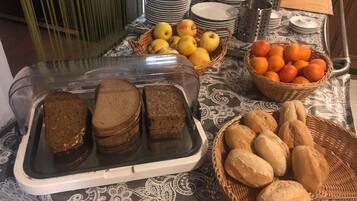 Una mesa de buffet con pan, frutas y platos.