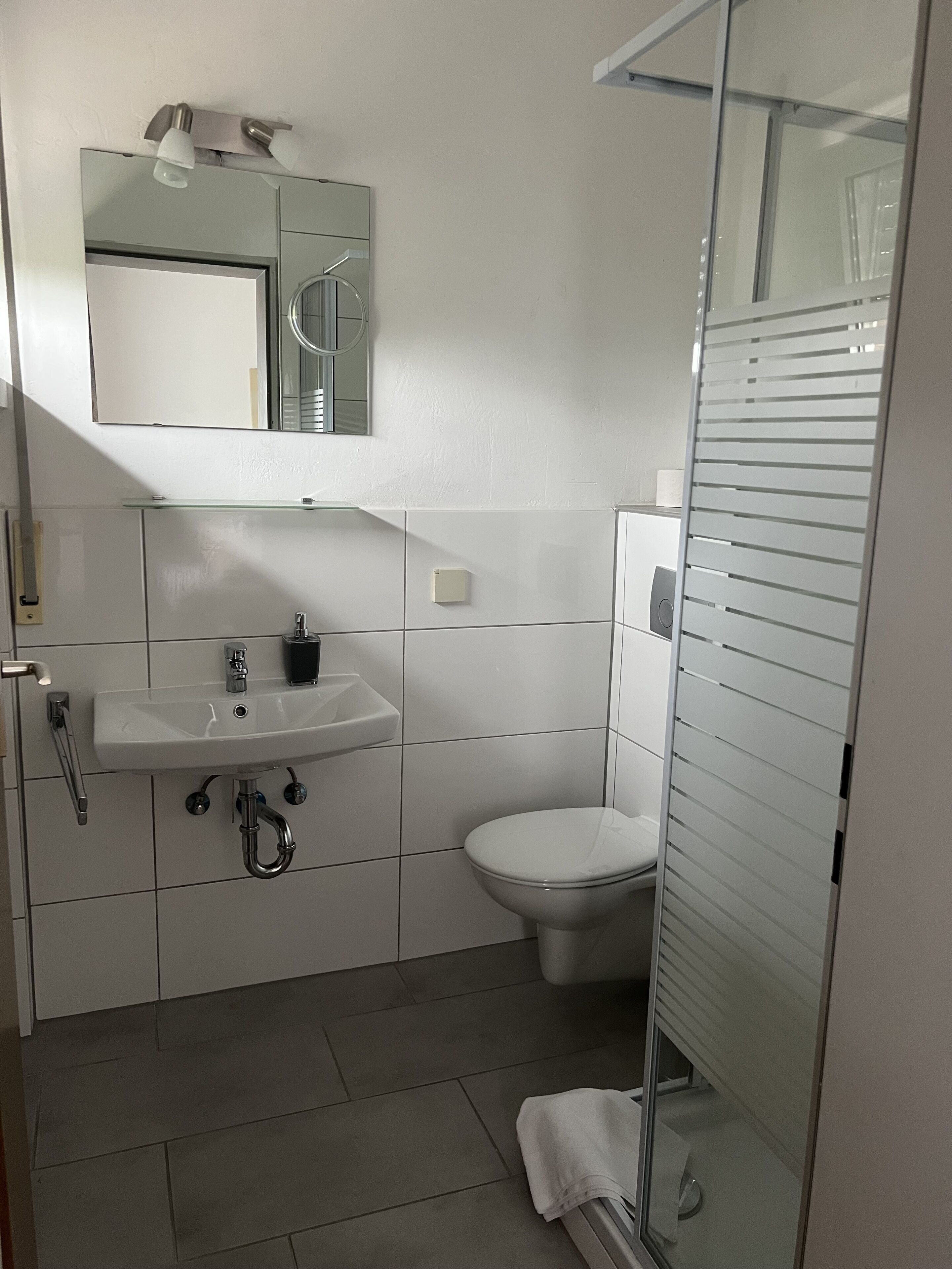 Une salle de bain moderne avec un lavabo blanc, un miroir et des toilettes.