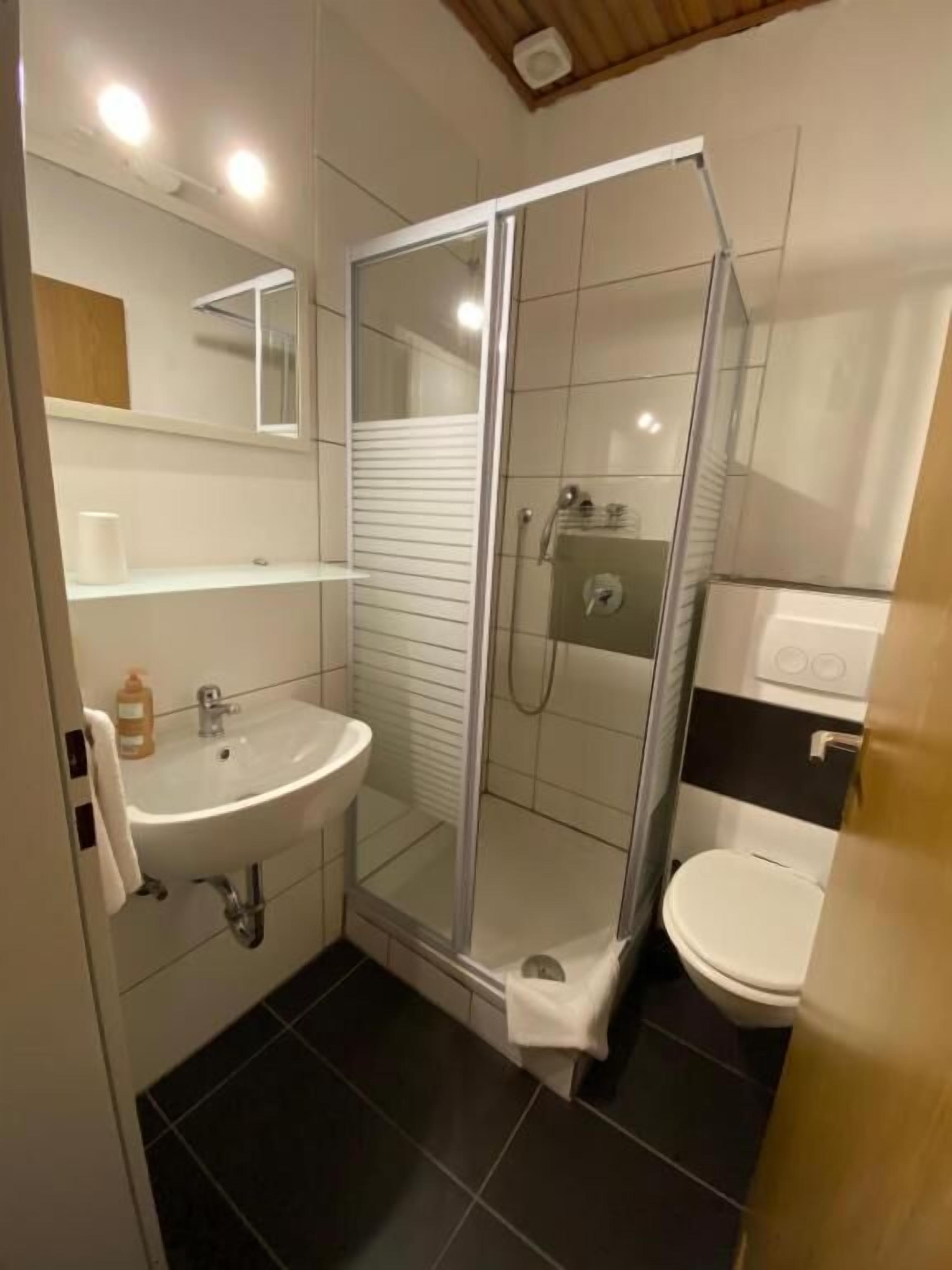 Un baño moderno con ducha de vidrio, lavamanos e inodoro.