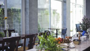 A dining area with a marble table, chairs, and a view through large windows. - The Present Home Hoi An (Da Nang)