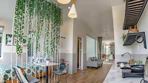 A spacious living room with a high ceiling, a dining area, and a kitchen with modern appliances. - The Present Home Hoi An (Da Nang)