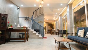 A spacious living area with a staircase, a dining table, and a sofa. - The Present Home Hoi An (Da Nang)