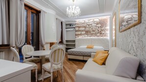 A cozy room with a bed, a sofa, a dining table with chairs, and a small kitchen area.