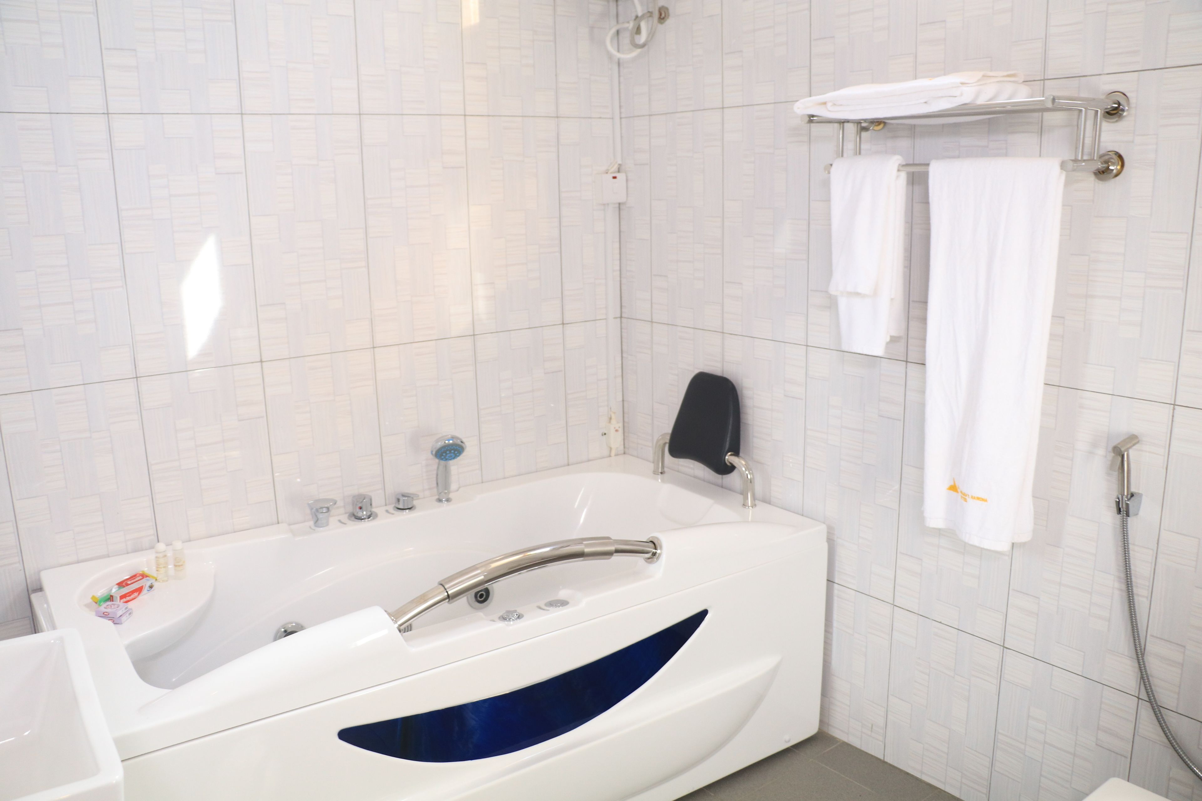 Un baño moderno con una bañera grande, una zona de ducha y un perchero con varias toallas.