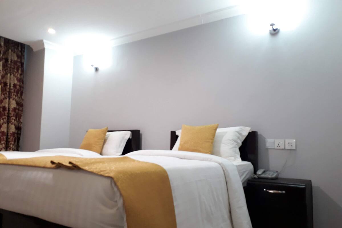 A bedroom with a bed, bedside tables, and a wall socket.