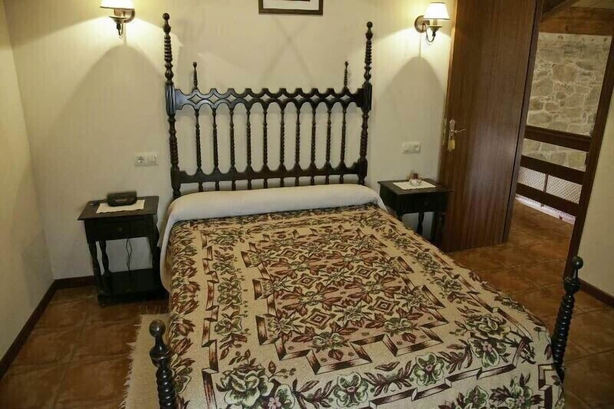 A bedroom with a four-poster bed, two bedside tables, and a patterned bedspread.