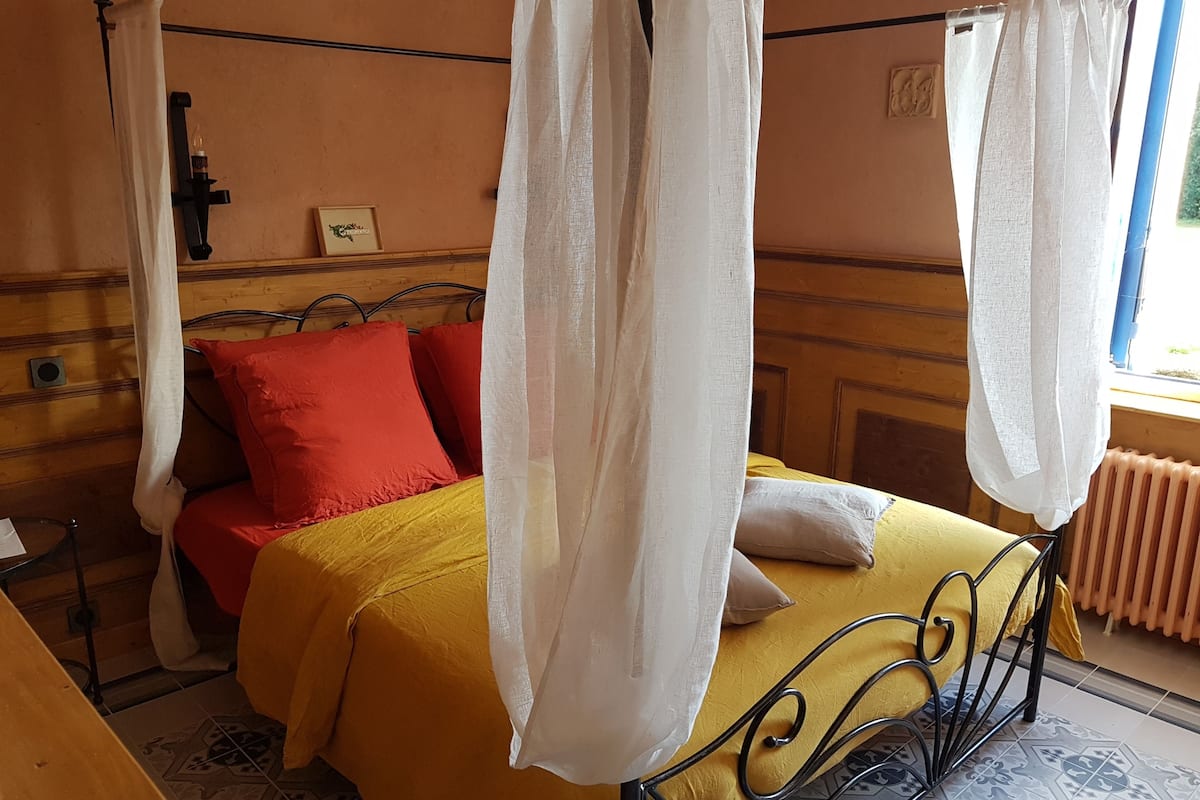Un lit à baldaquin, une table de chevet et un radiateur.