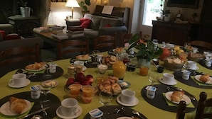 A dining area with a round table set for breakfast, surrounded by chairs. - La Maison des Gardes - Chambres d'hôtes (Cluny)