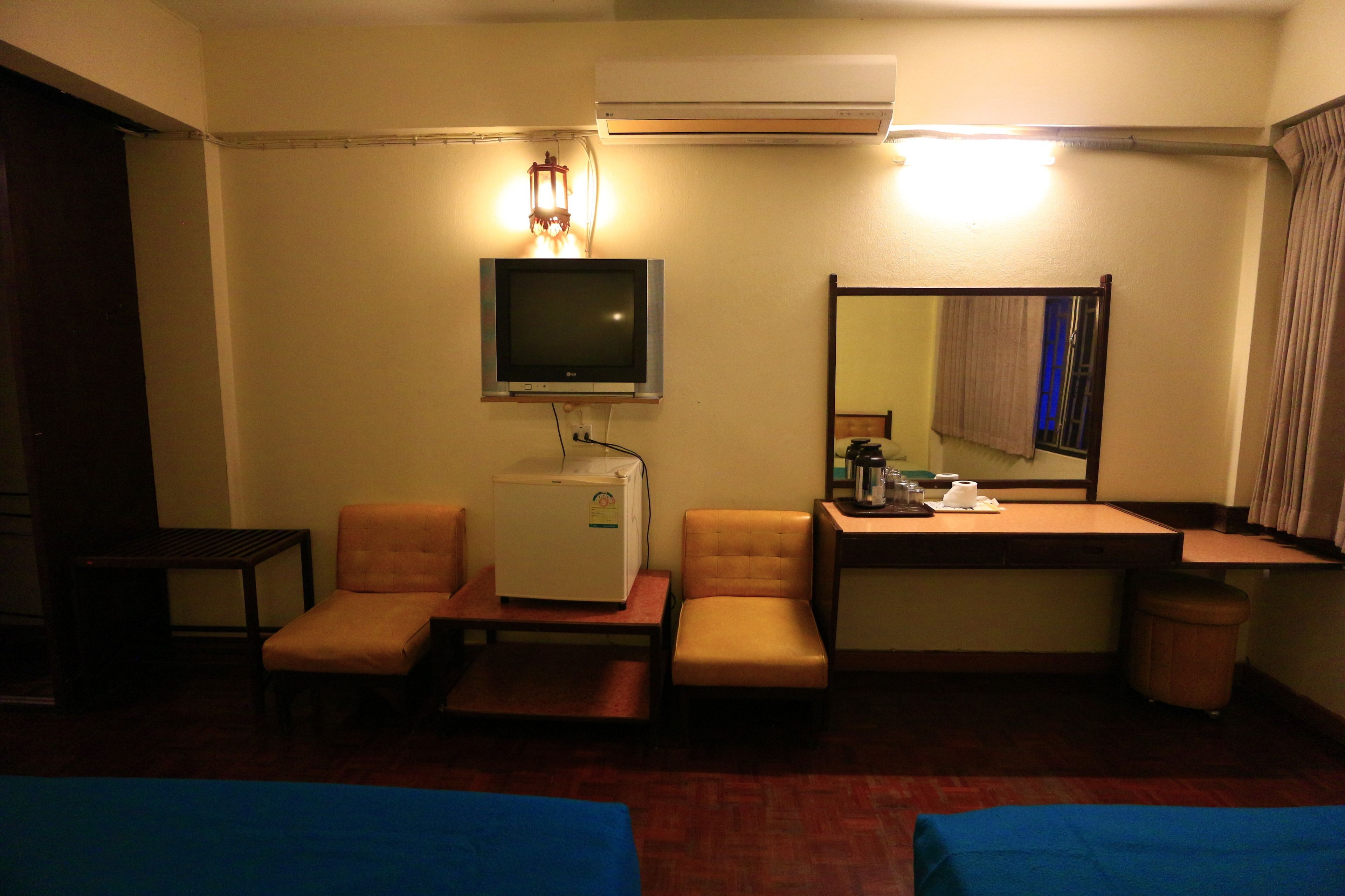 Ein Hotelzimmer mit einem Bett, einem Schreibtisch, einem Sessel, einem Fernseher und einem Spiegel.