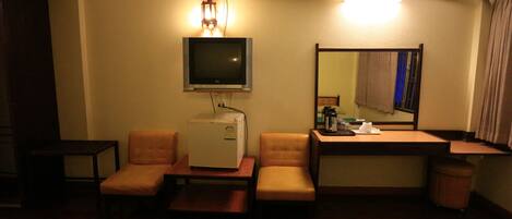 Ein Hotelzimmer mit einem Bett, einem Schreibtisch, einem Sessel, einem Fernseher und einem Spiegel.