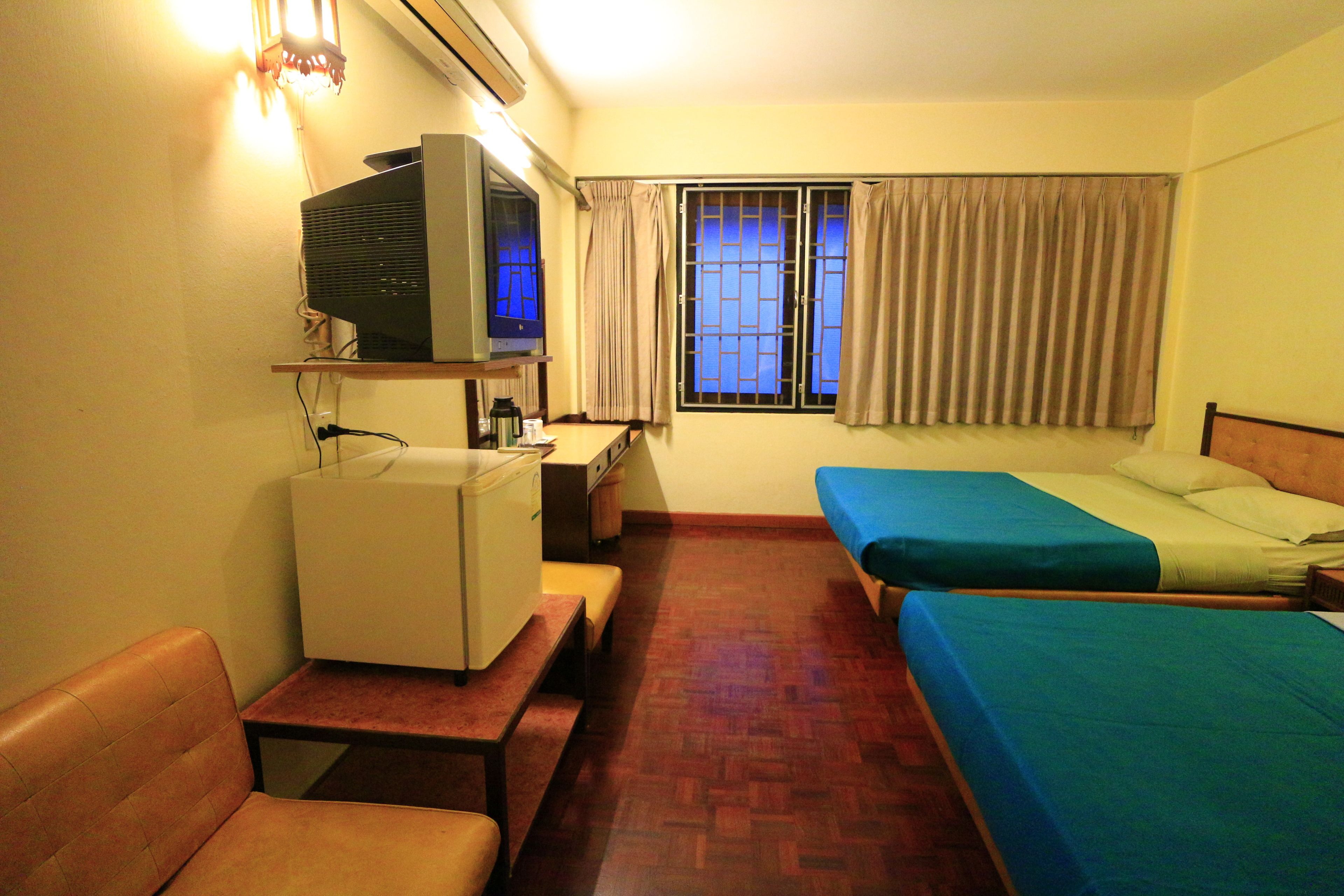 A hotel room with a desk, two beds, a chair, and a television.