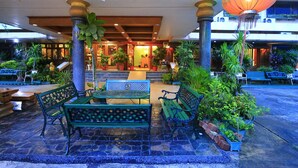 An outdoor seating area with green benches and a table, surrounded by potted plants and a decorative lantern. - Anodard Hotel Chiang Mai (Chiang Mai)