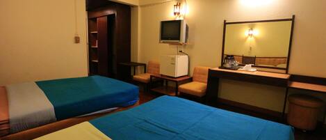 A hotel room with two beds, a desk, a chair, a television, and a mirror.