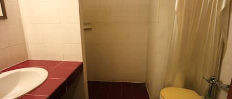 Un baño con inodoro blanco, lavabo rojo y cortina de ducha.