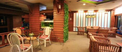 A restaurant with wicker chairs, a glass table, and a green wall.