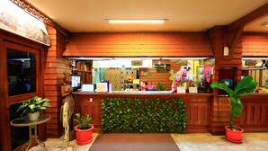 A reception area with a wooden reception desk, a computer, and a green plant. - Anodard Hotel Chiang Mai (Chiang Mai)