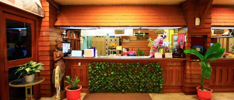 A reception area with a wooden reception desk, a computer, and a green plant.