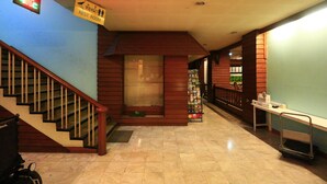 A hotel corridor with a staircase, a rest room sign, a vending machine, and a cart. - Anodard Hotel Chiang Mai (Chiang Mai)