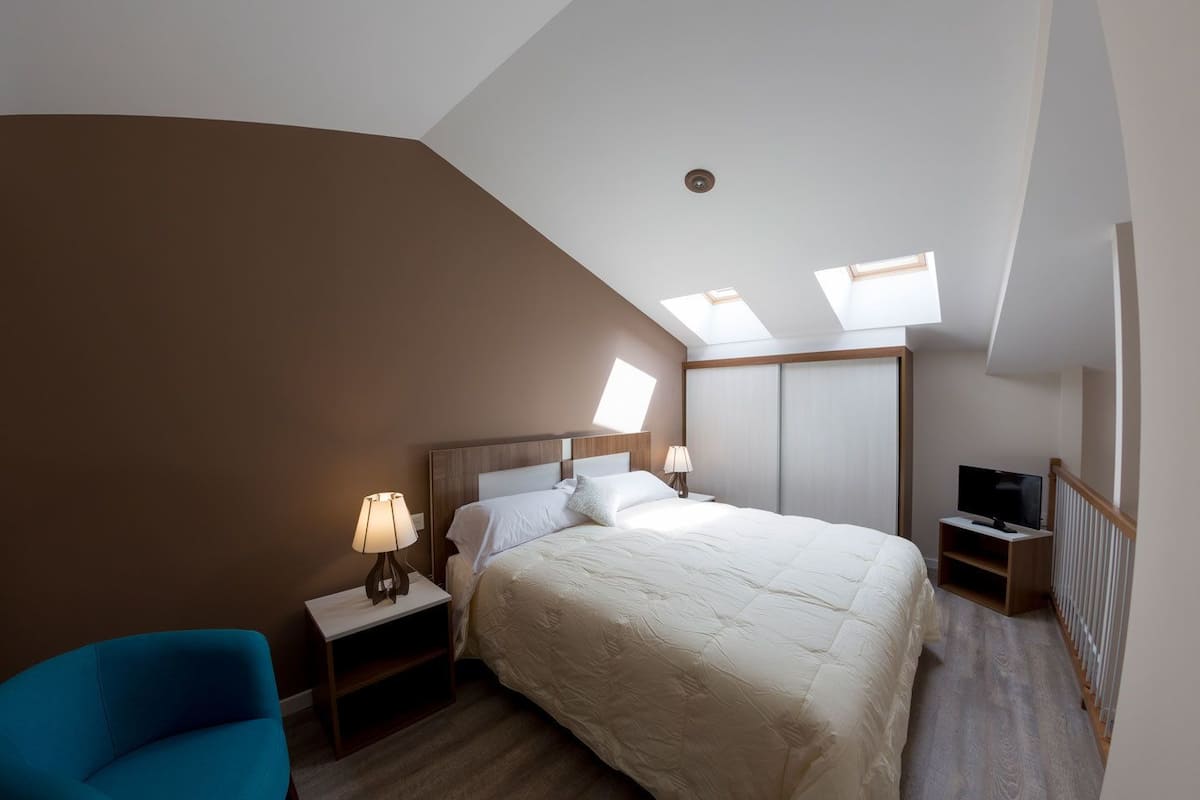 Une chambre à coucher avec un lit, une table de chevet, un téléviseur et une chaise.
