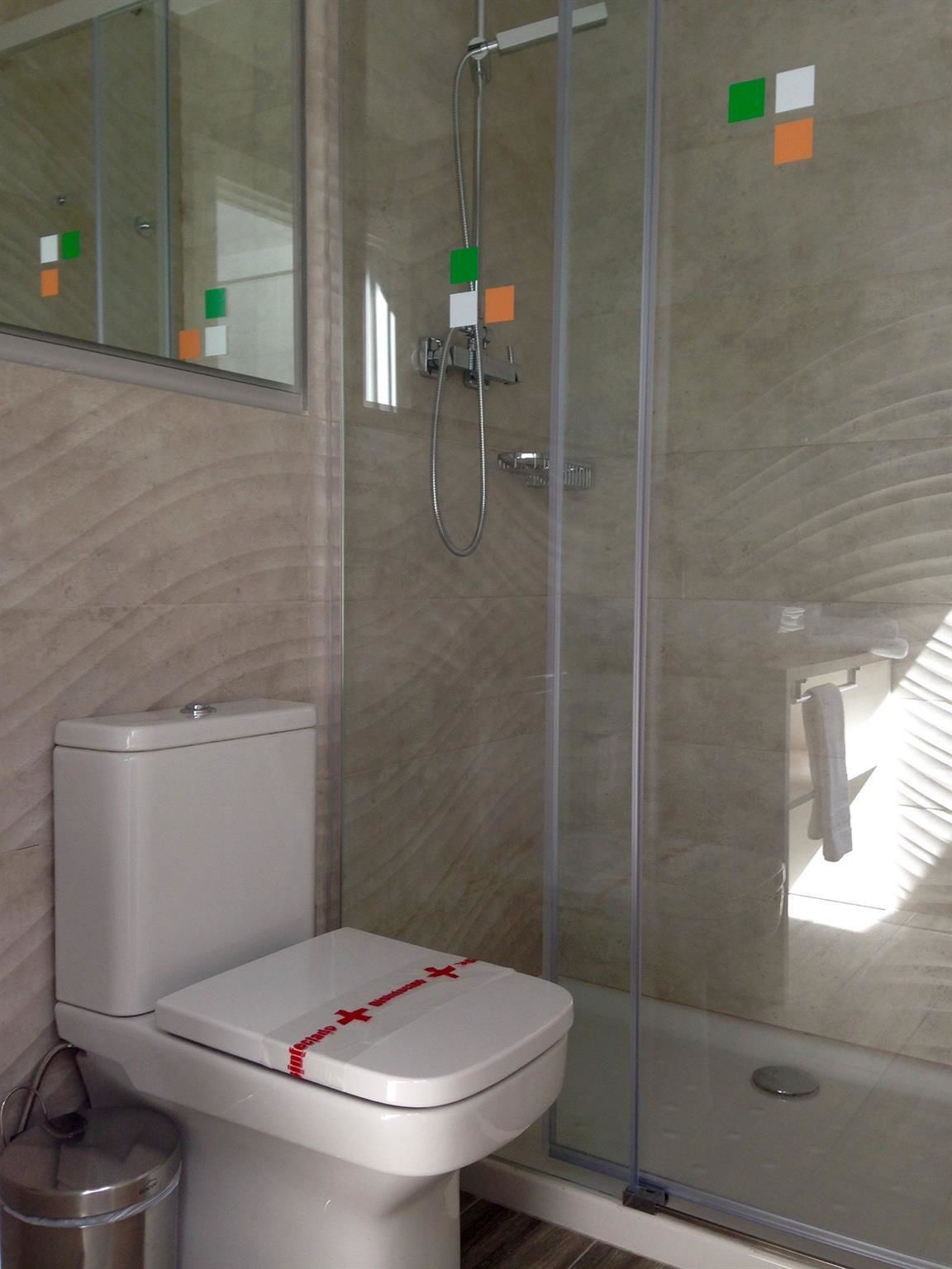 A bathroom with a toilet, a glass shower enclosure, and a mirror.