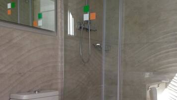 A bathroom with a toilet, a glass shower enclosure, and a mirror.