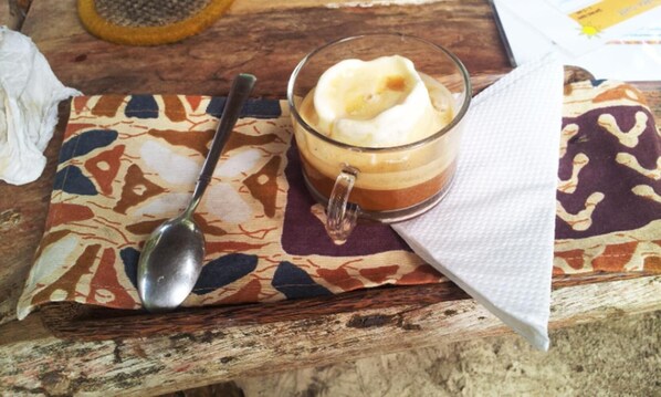 A layered beverage in a glass with a spoon on a patterned cloth.