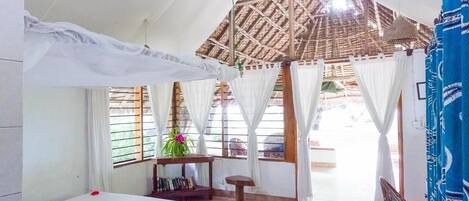 Una habitación con una cama, una mesita pequeña, una silla y una lámpara colgante.