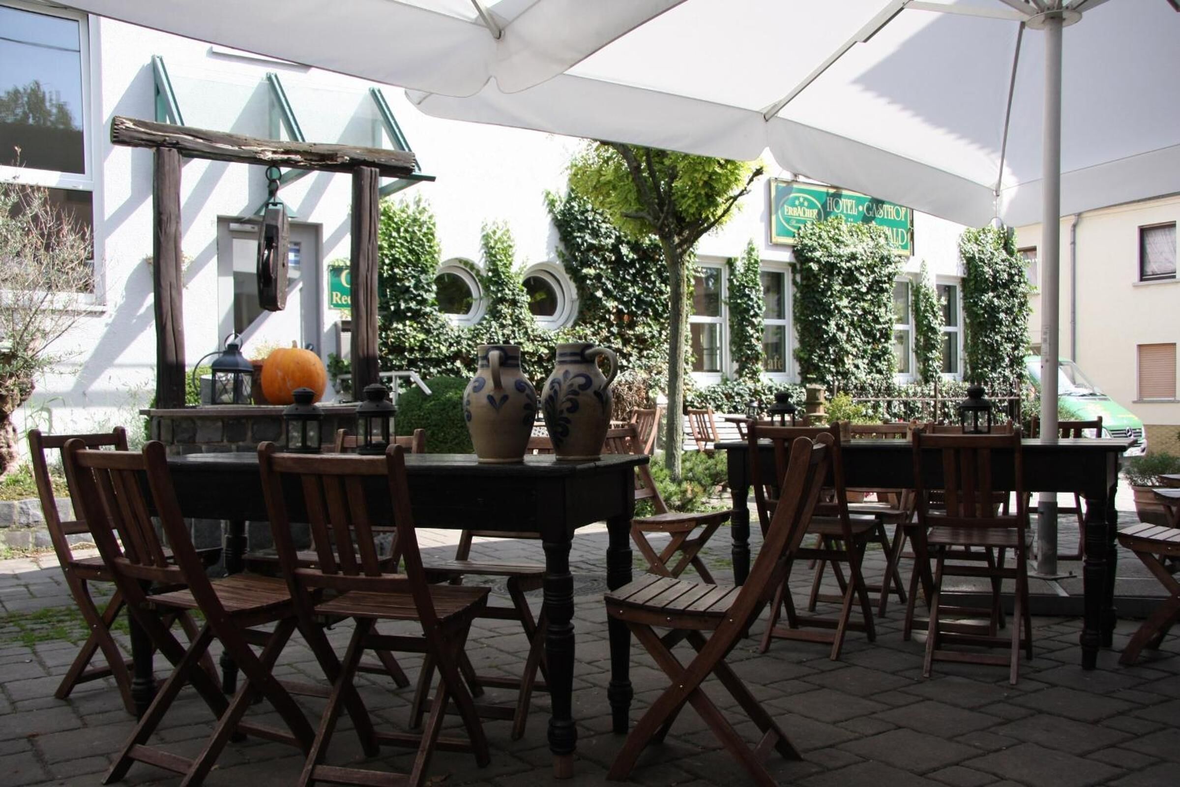 An outdoor dining area with wooden tables and chairs, surrounded by a white canopy.