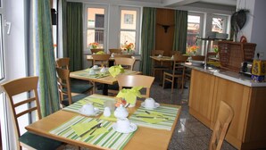 A dining area with tables set for breakfast, featuring striped placemats, white cups, and green napkins. - Hotel Gasthof Gruener Wald (Hofheim am Taunus)