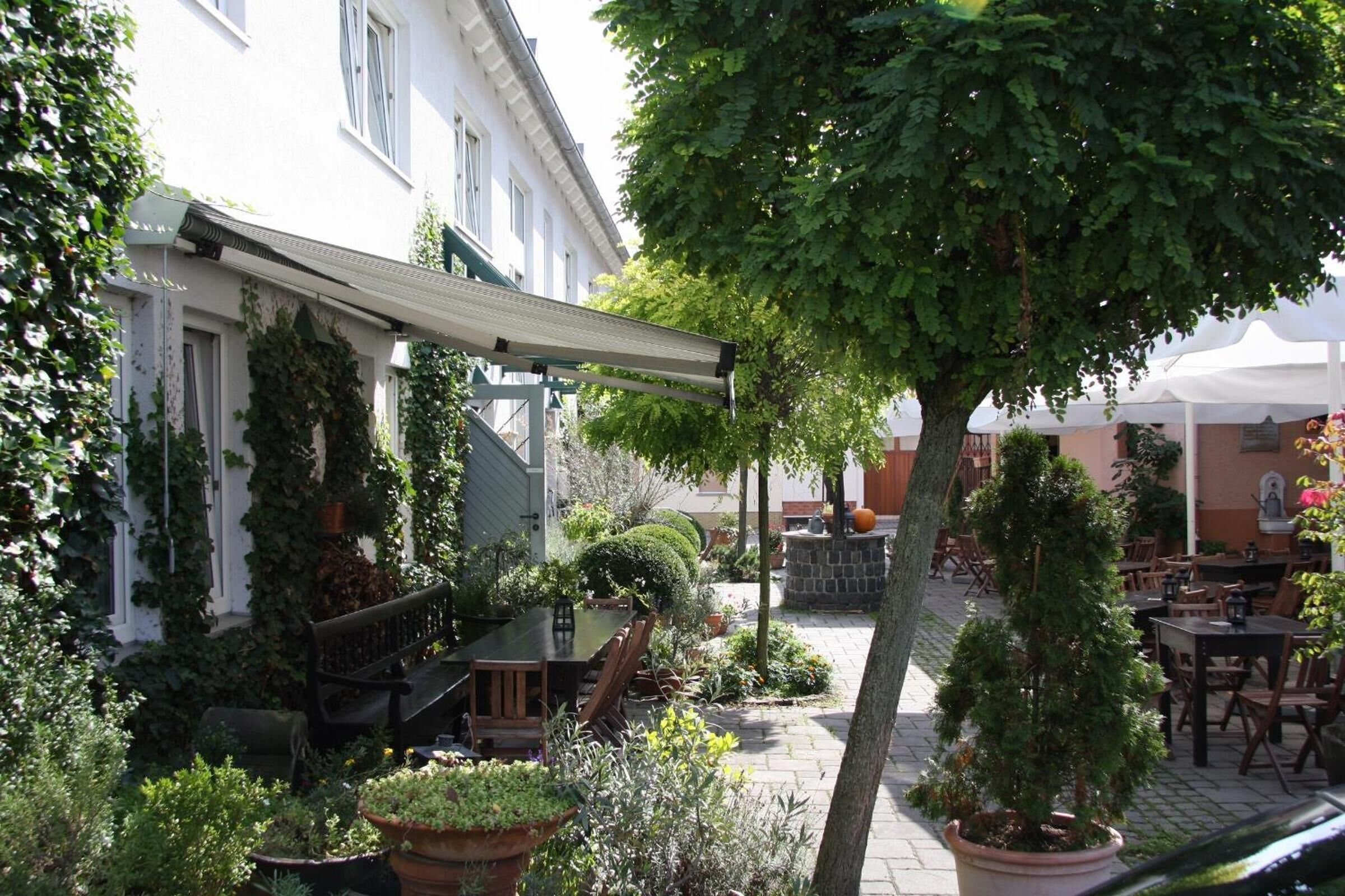 A courtyard with outdoor seating, potted plants, and a pergola.