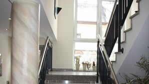 A staircase with granite steps, black handrails, and a large marble column. - Hotel Gasthof Gruener Wald (Hofheim am Taunus)