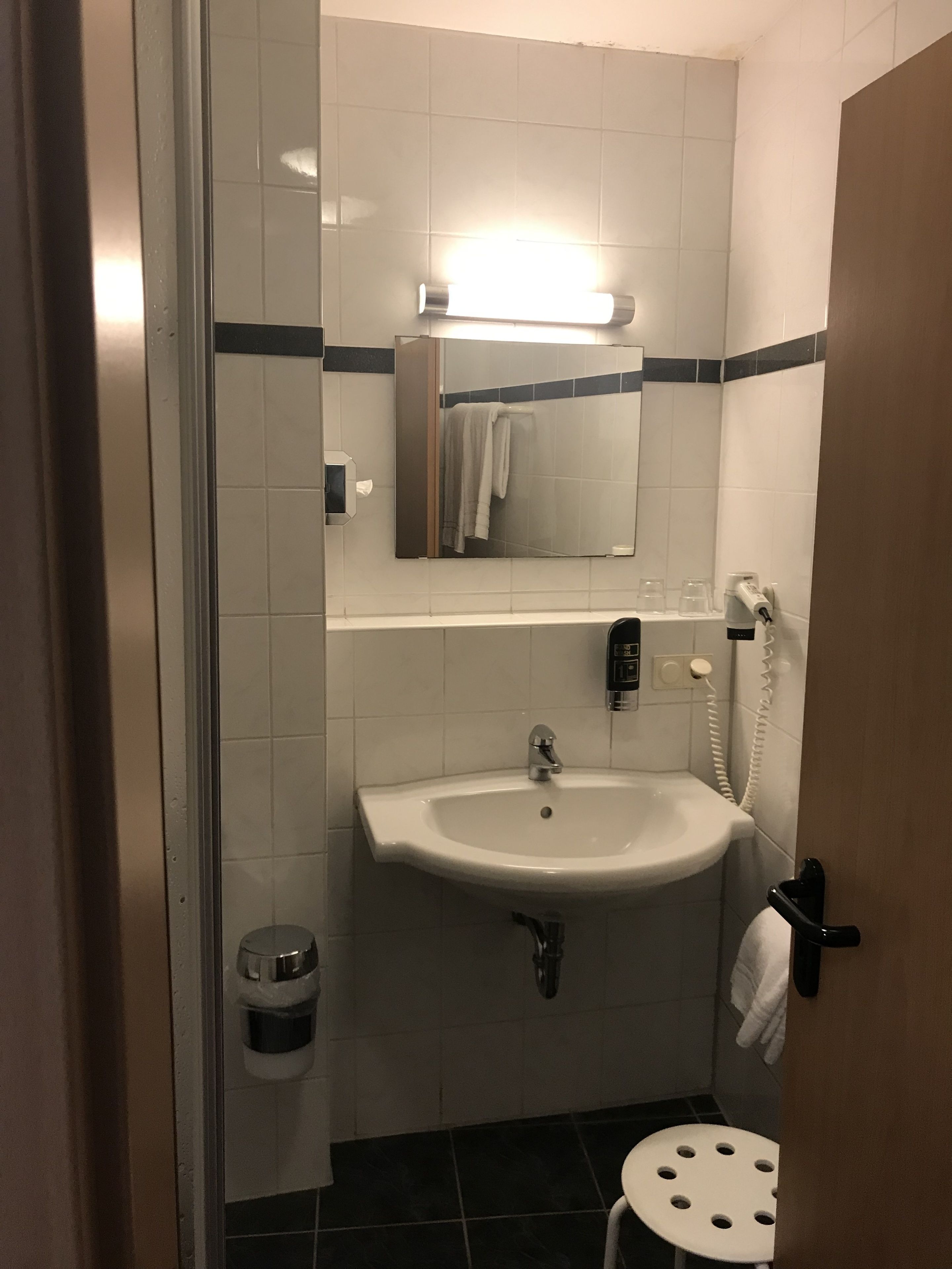 A small bathroom with a sink, mirror, and towel rack.