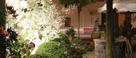 A garden area with a stone bench, potted plants, and a tree.