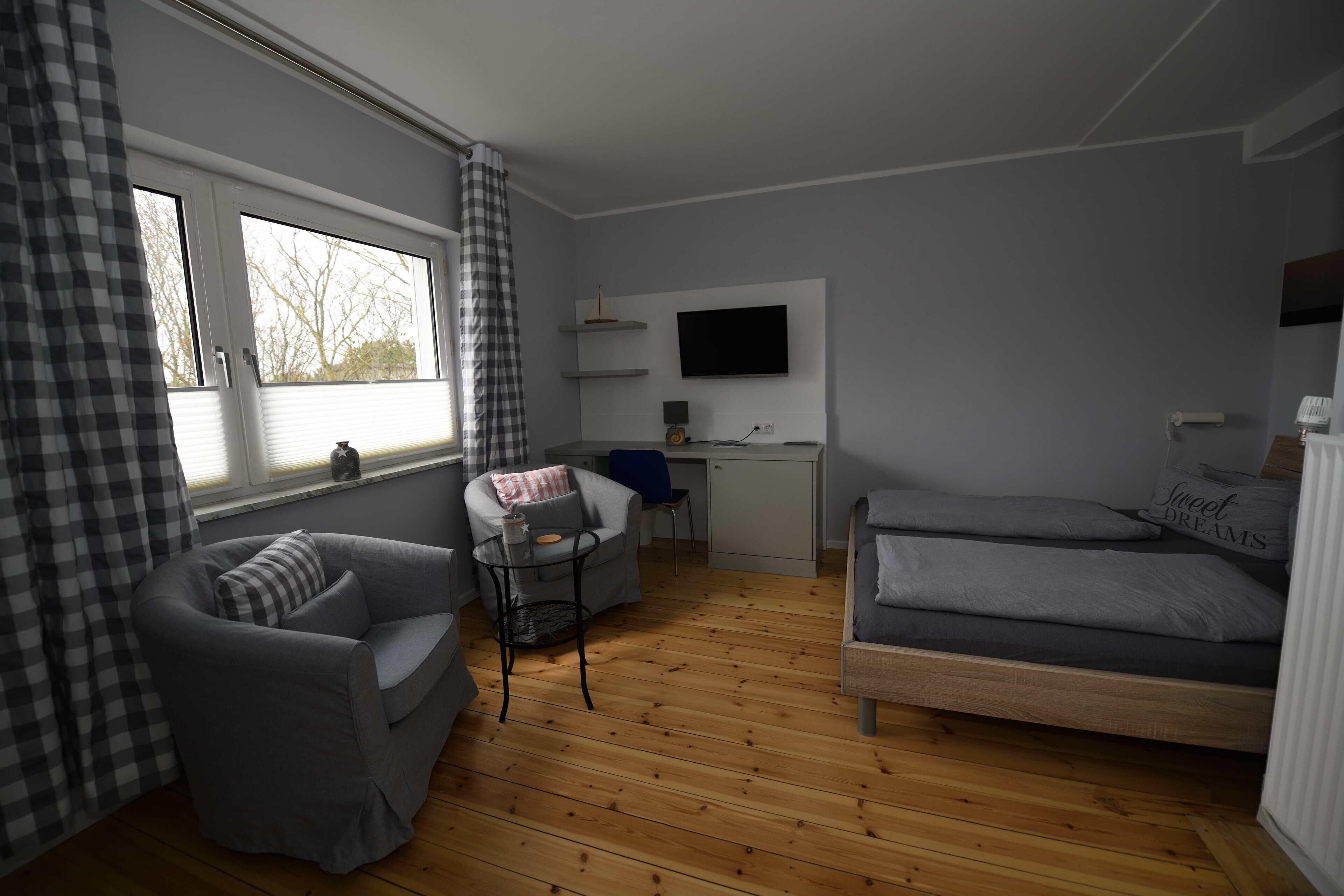 Ein kleines Zimmer mit einem Bett, einem Schreibtisch, einem Sessel und einer Couch.