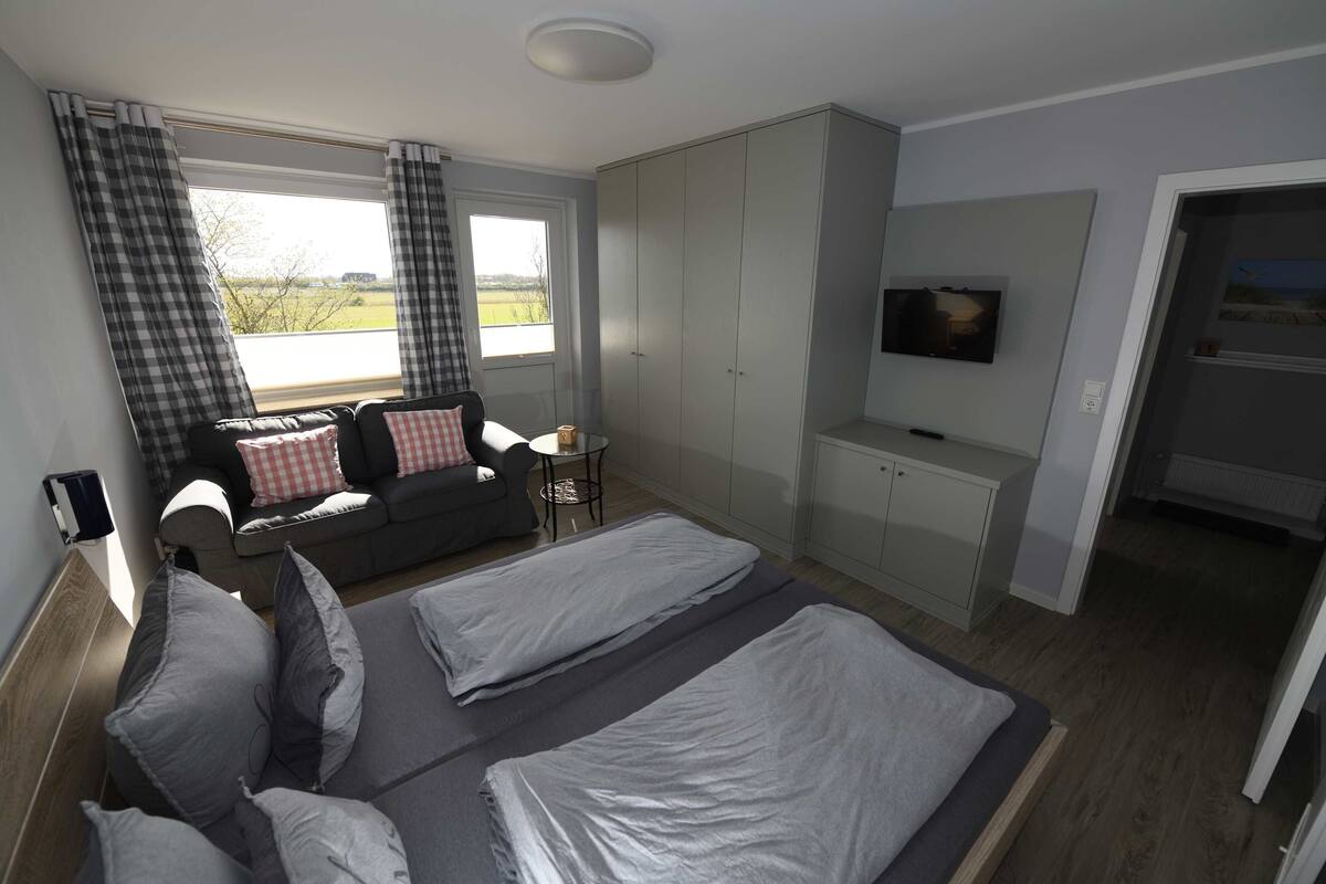 A bedroom with a bed, a sofa, a TV, and a wardrobe.