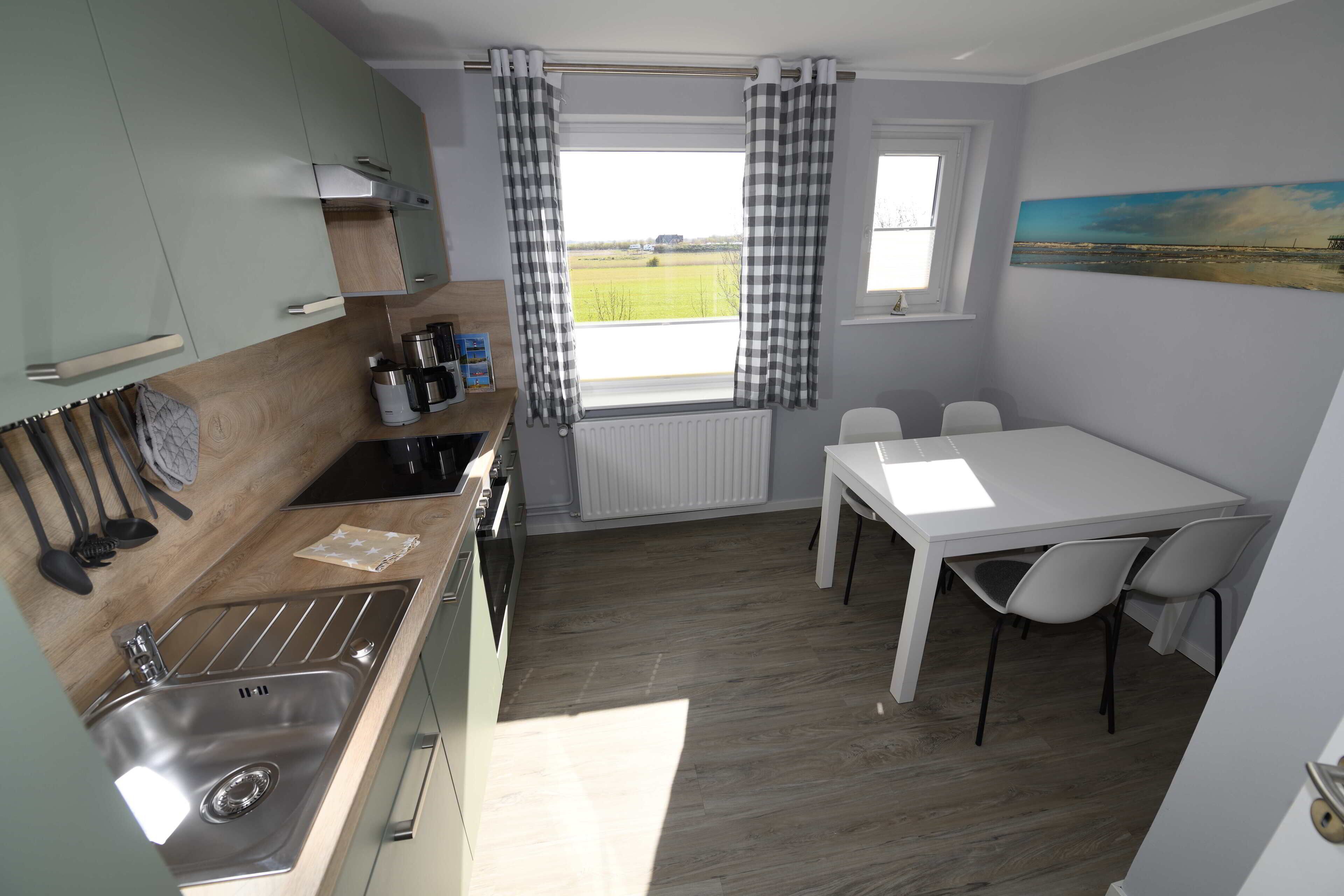 A compact kitchen with a sink, stove, and dining area with chairs.
