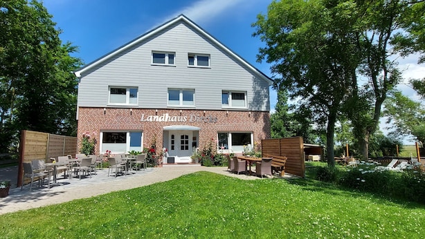 A two-story building with a brick facade and a sign reading "Landhaus Dachs". - Landhaus Dircks (St. Peter-Ording)