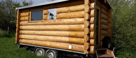 Una cabaña de madera sobre ruedas, con ventana y puerta.
