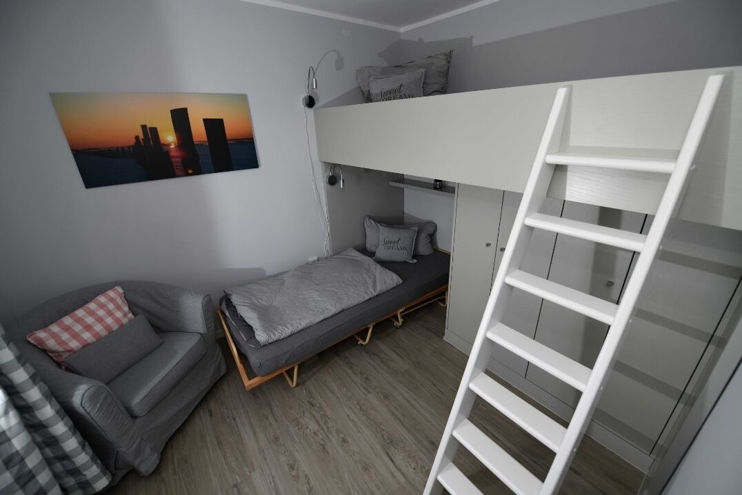 A compact room with a bunk bed, a sofa, and a ladder.