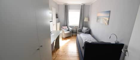 A compact room with a bed, a desk, and a chair.