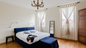 A bedroom with a large bed, bedside tables, a mirror, and a chandelier. - Residenza Del Cedro (Rome)
