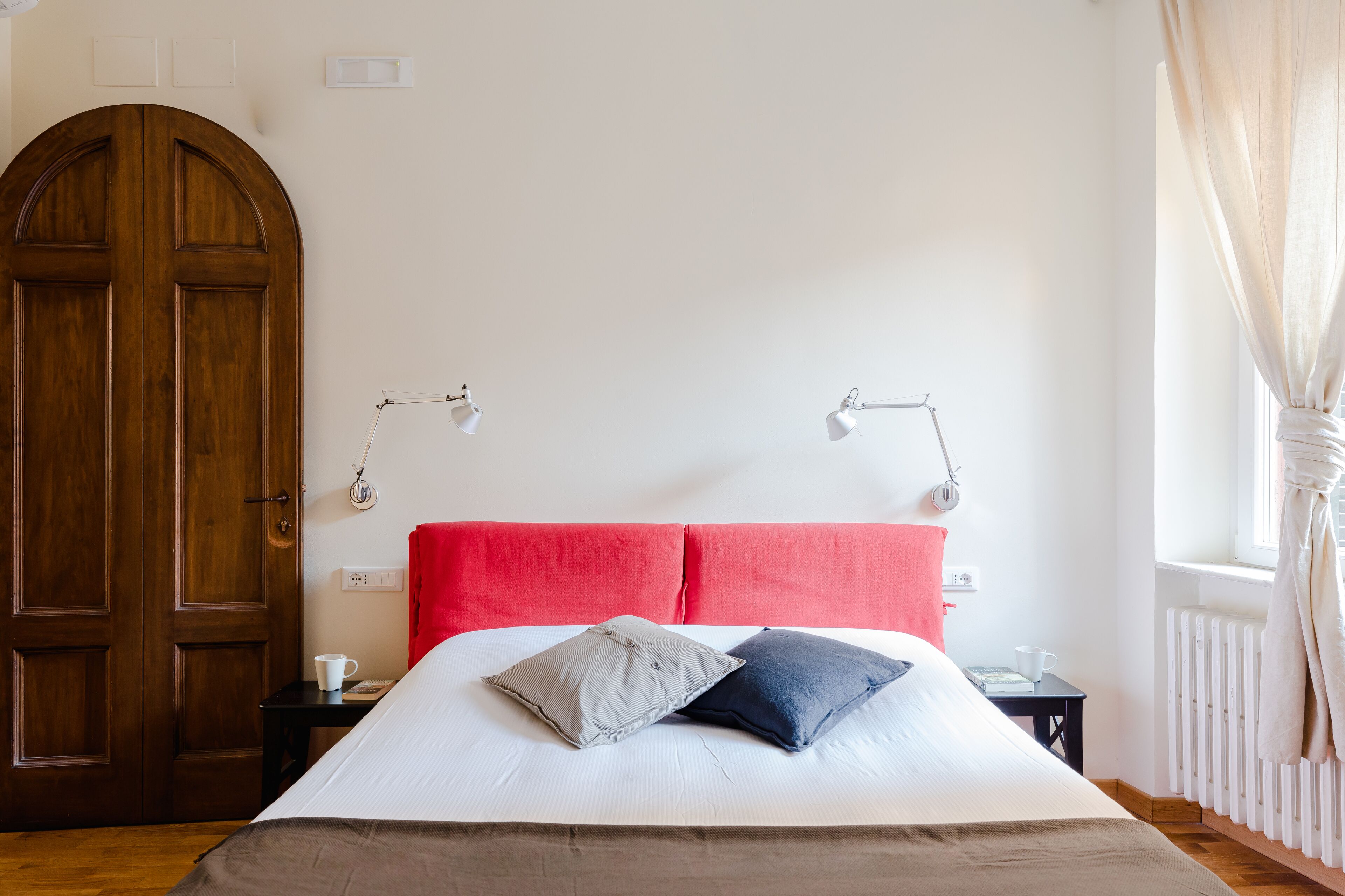 Une chambre à coucher avec un grand lit, deux lampes de chevet, une porte en bois et un radiateur.